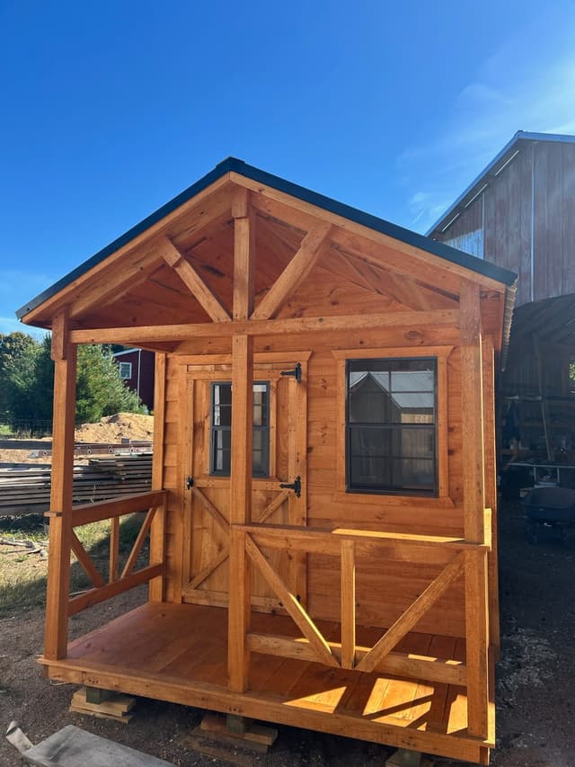 Front exterior view of a cabin-style tiny home on a trailer